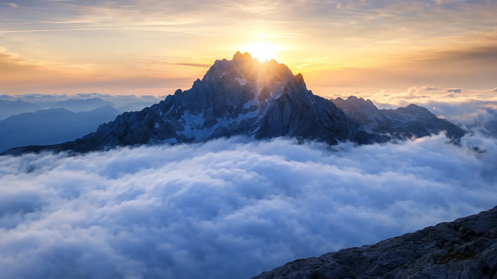 Montanha acima das nuvens iluminada pelo amanhecer.